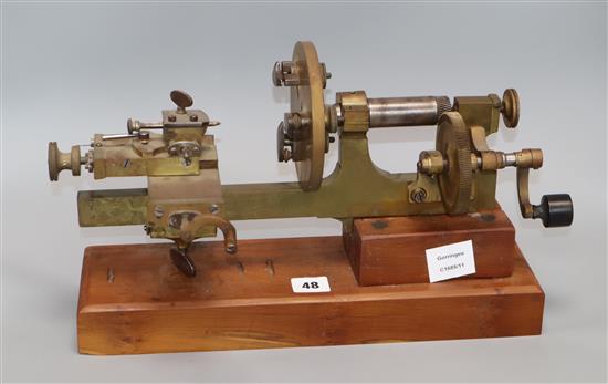 An early 20th century brass and steel clockmakers lathe, on mahogany plinth